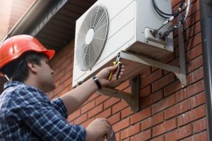 Technician performs air conditioner repair on an outdoor unit.